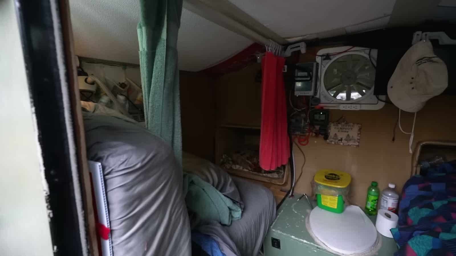 Interior wall of a foam teardrop trailer with vent fan, hanging curtain, and bed