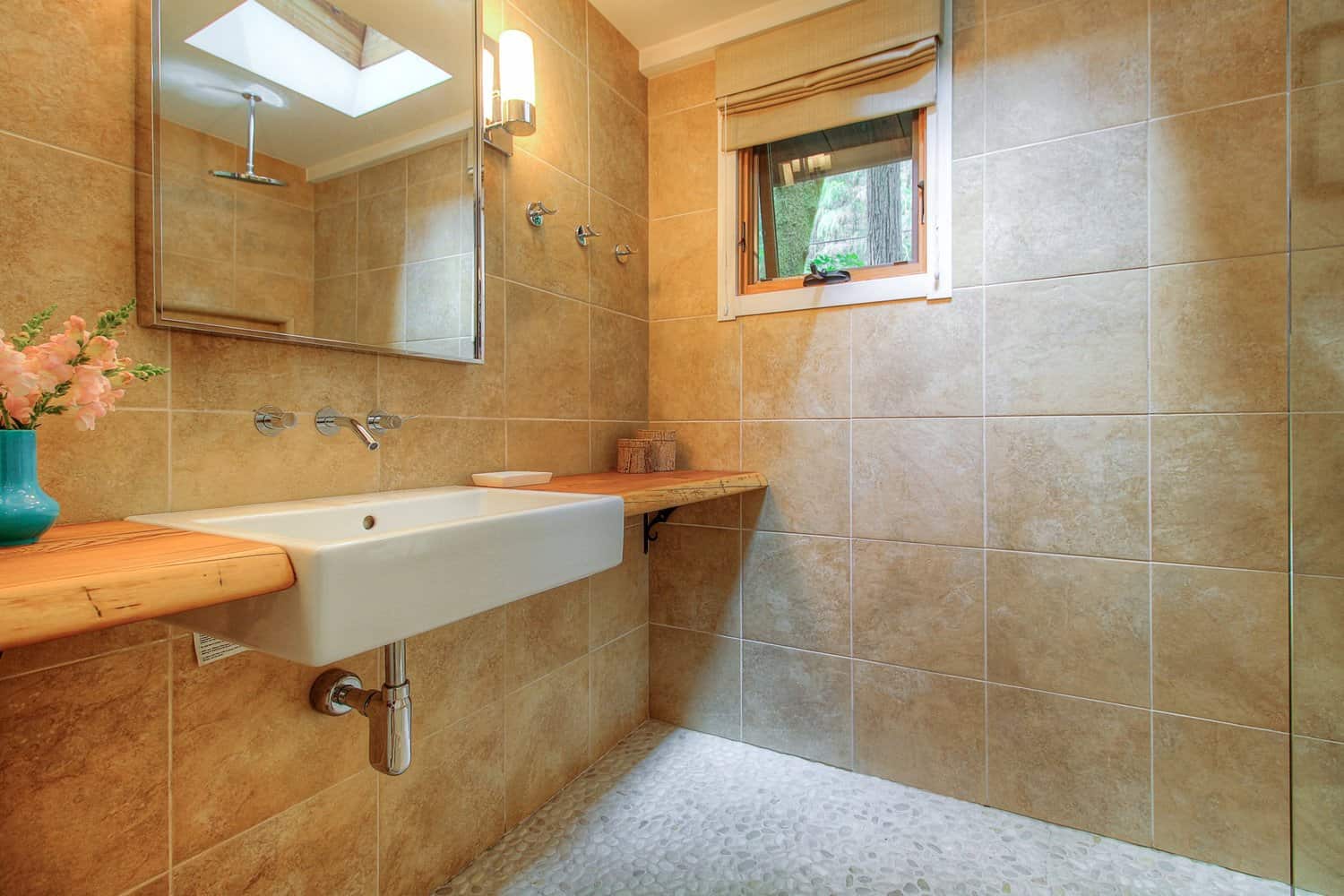 Bathroom with tile walls, a wide floating sink, and a skylight