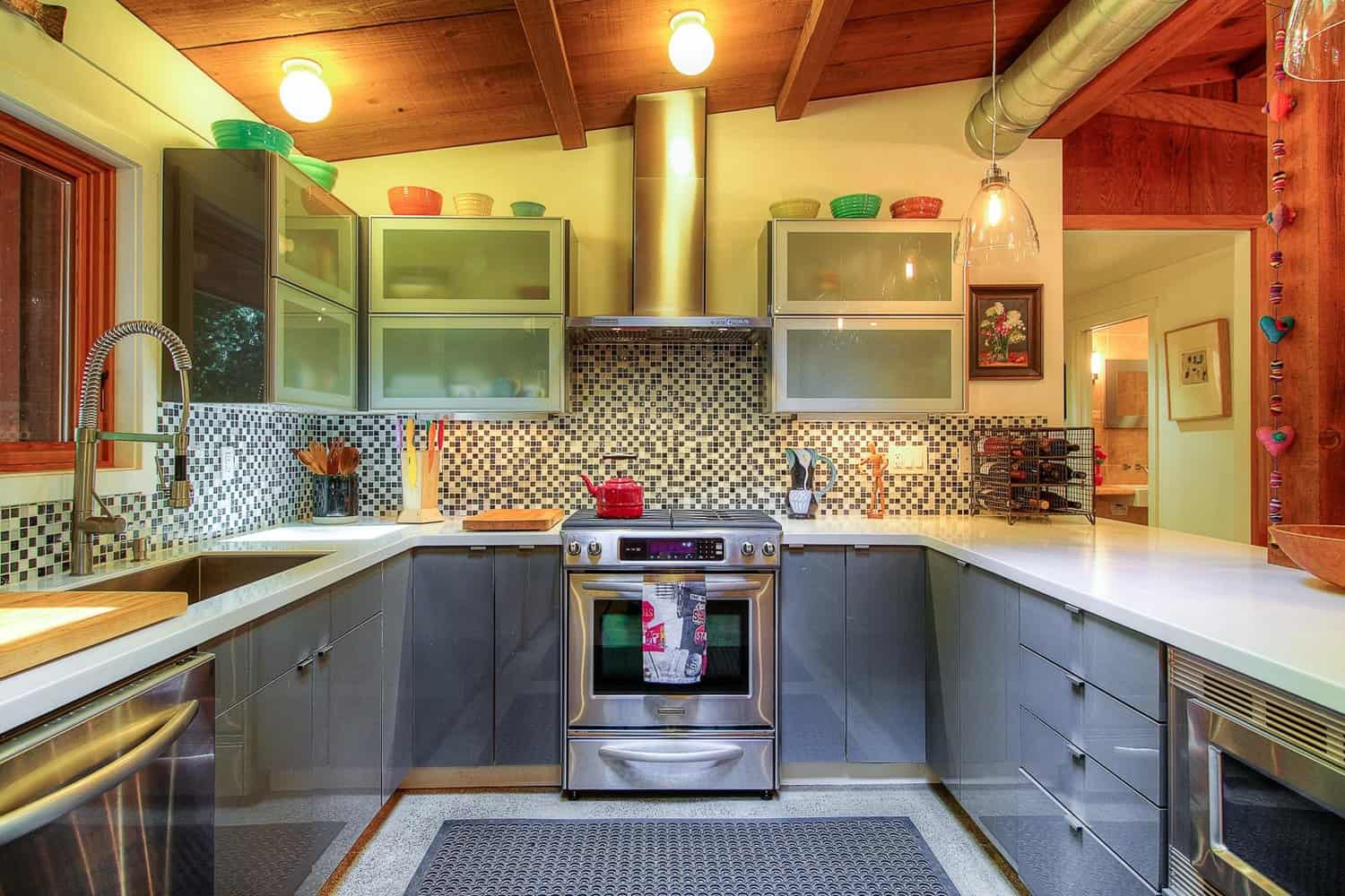 Kitchen with grey cabinets, stainless range and hood, mosaic tile backsplash, and wood ceiling