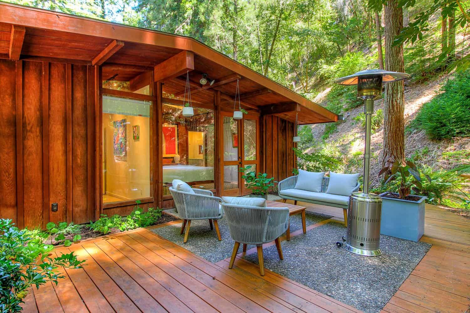 Patio with outdoor seating and a patio heater beside the redwood cabin