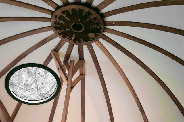 Luna ceiling: radial wood ribs, light curved panels, circular wood medallion with a forest-and-moon design, one small porthole