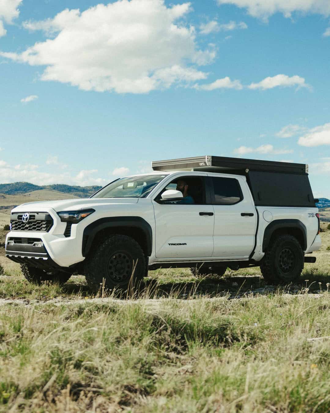 Go Fast Campers V2 Pro closed low-profile camper on a white Toyota Tacoma in open grassland