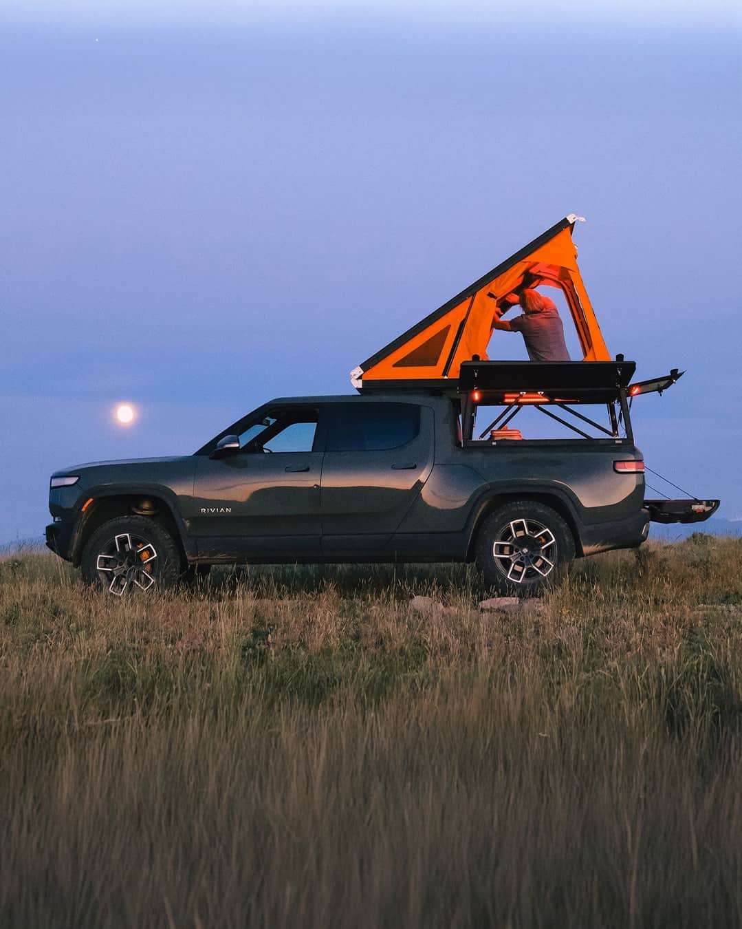 Go Fast Campers V2 Pro orange wedge tent glowing at dusk with side panel open