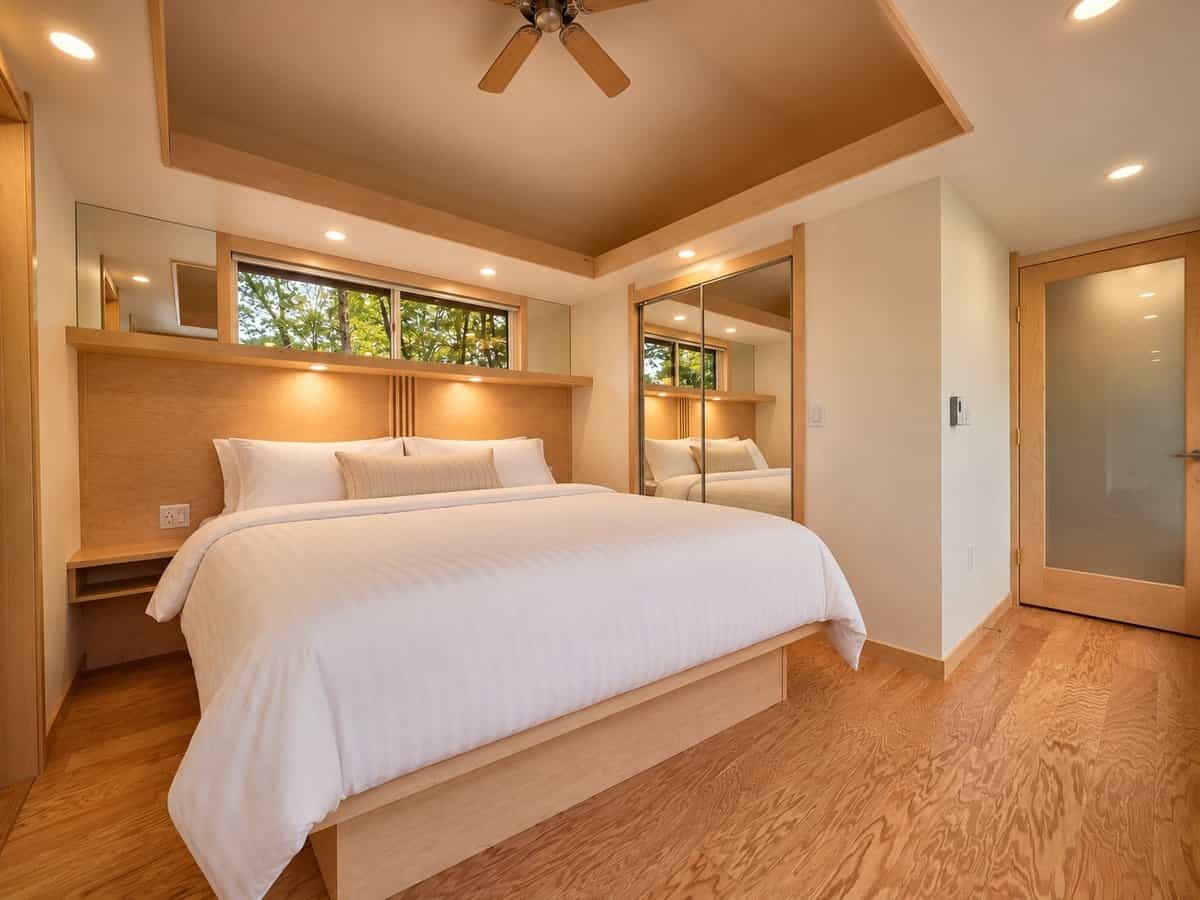 Private king bedroom with a built-in maple headboard, reading lights, clerestory window and mirrored closet doors in the GLASS HOUSE Lot 25