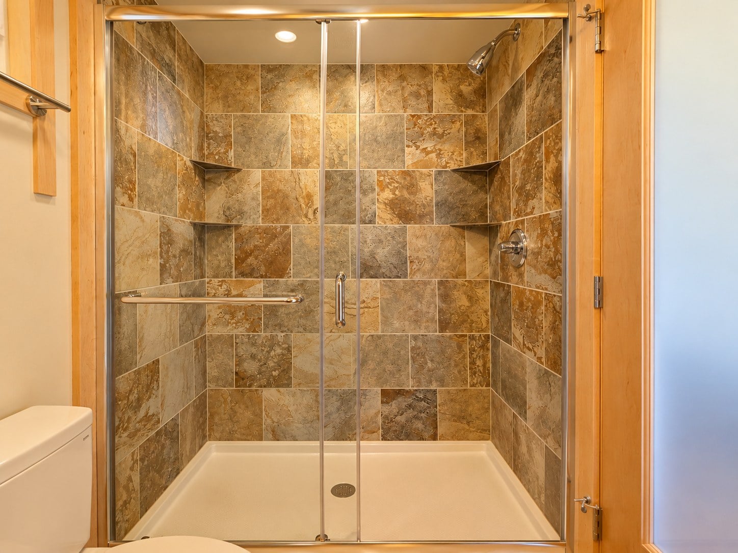 Custom tiled shower with stone-look tile, corner shelves and sliding glass doors in the Glass House Lot 27