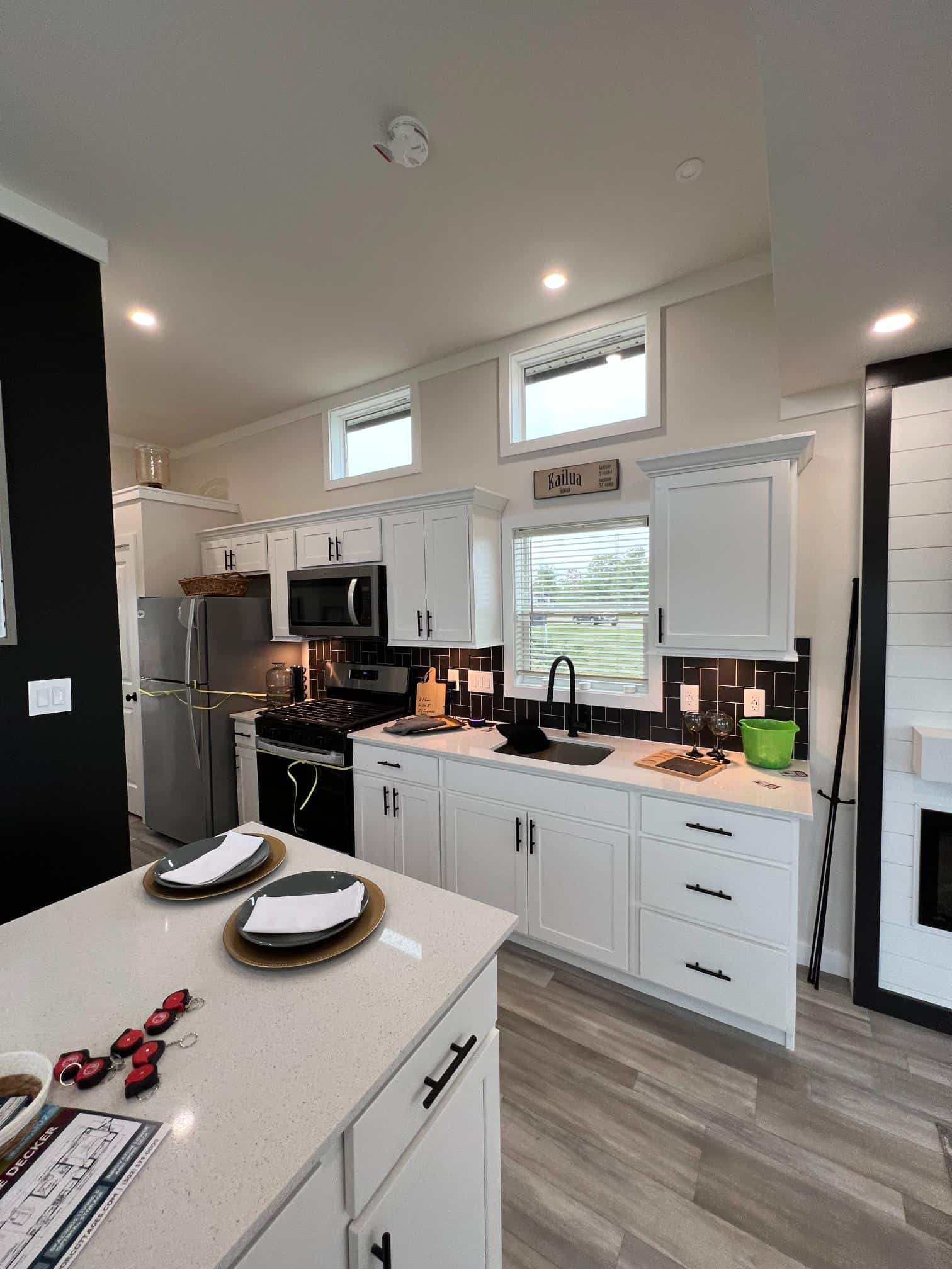 Bayview 300 kitchen with white cabinets, quartz counters, black backsplash, and stainless appliances