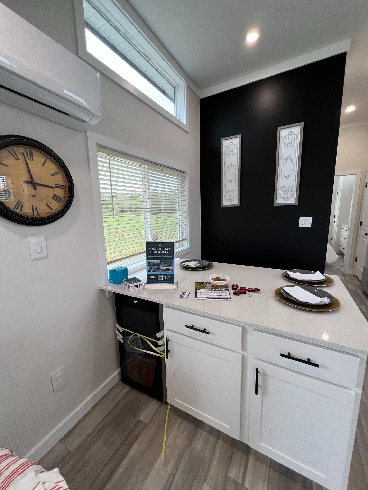 Bayview 300 white island with built-in wine fridge, black accent wall art, quartz counter place settings
