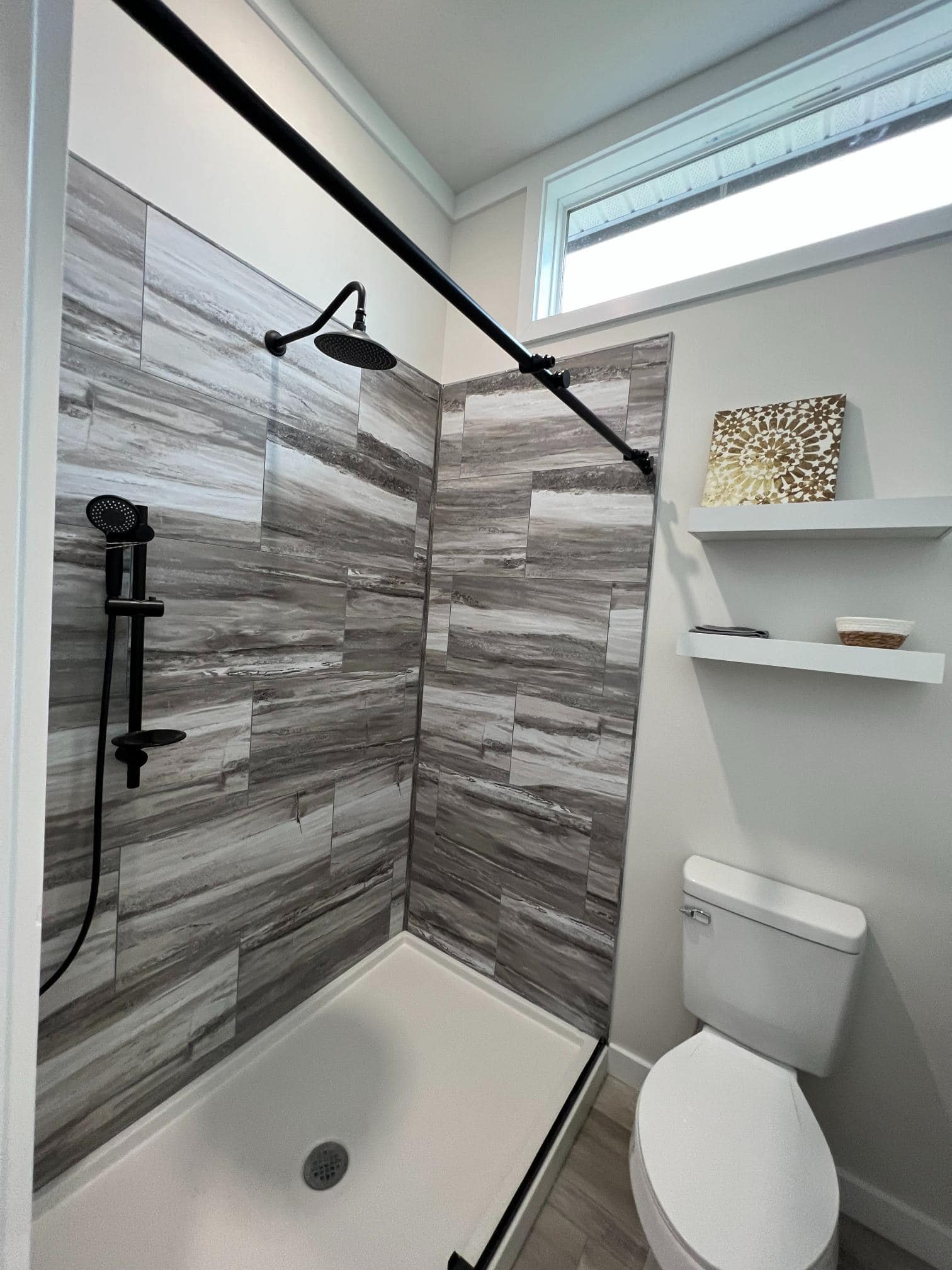 Walk-in shower with gray tile walls and a black rainfall showerhead