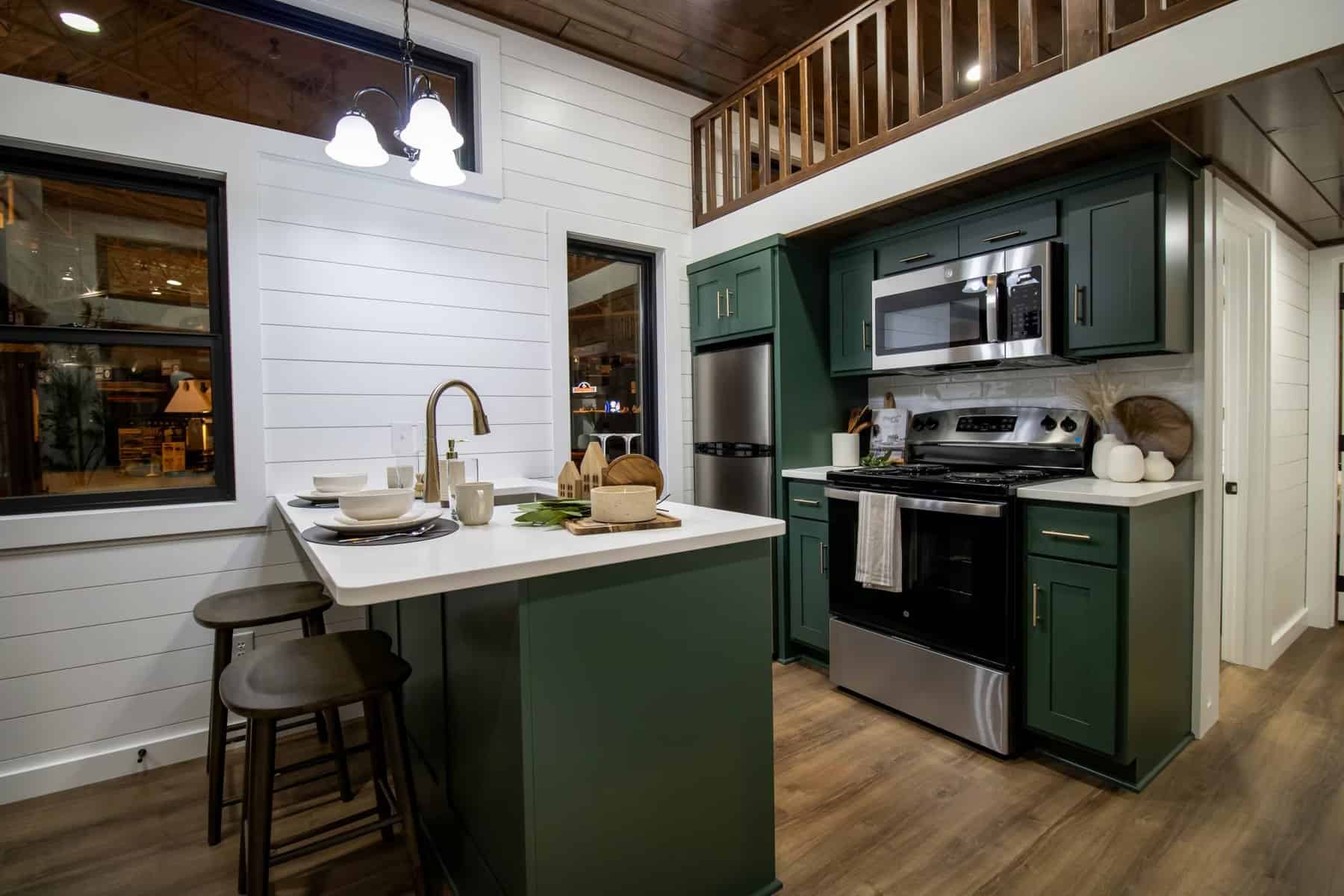 A-Frame Luxe kitchen with forest-green cabinets, quartz island with seating, stainless range, and pendant lights