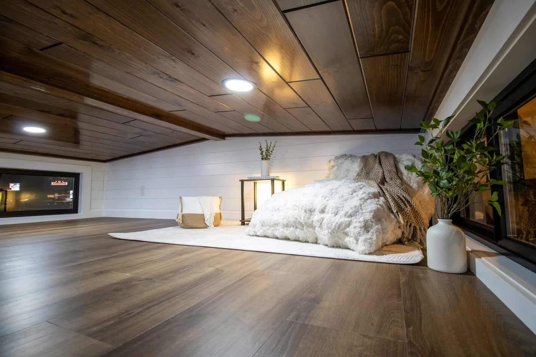 Wide view of the loft with wood ceiling, plank floor, and a bed by the railing