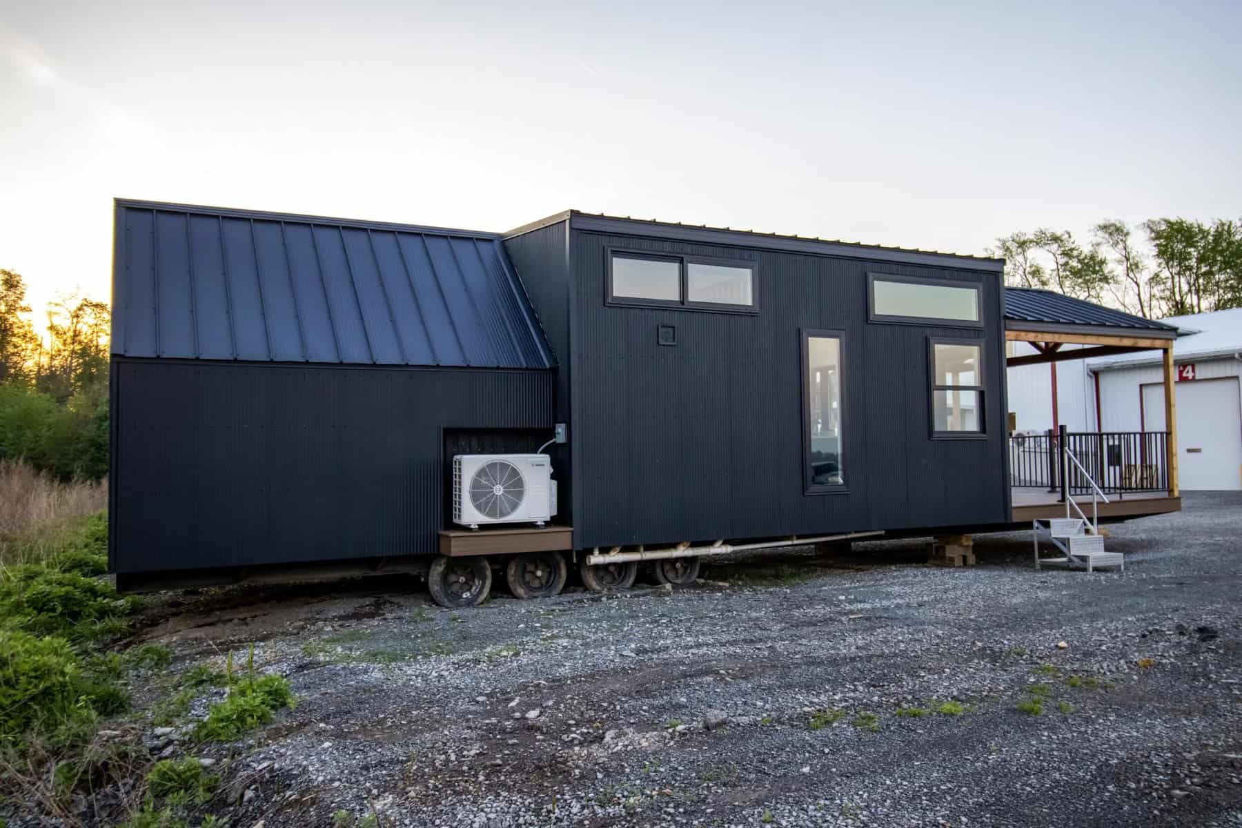 Rear view of the Great Lakes A-Frame Luxe with black metal siding, steep A-frame roof, and mini-split
