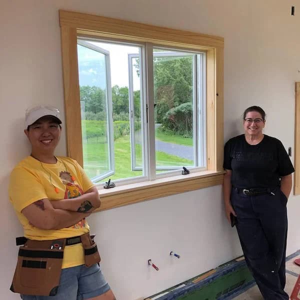 Two students stand beside a wood-trimmed window inside a Hammerstone tiny house