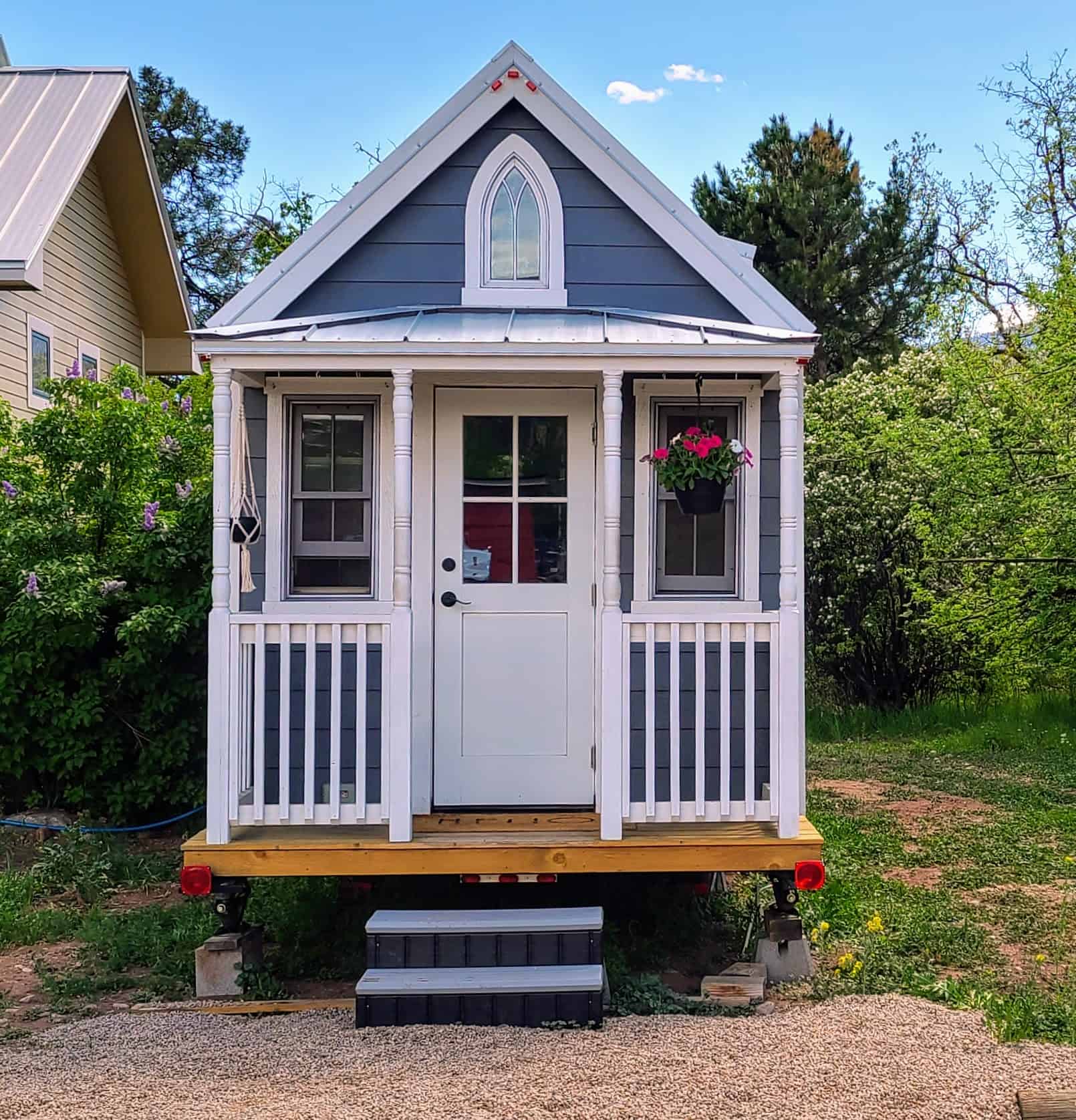 Blue cottage-style tiny house front porch on a gravel pad at Hermosa Orchards Village in Durango, Colorado