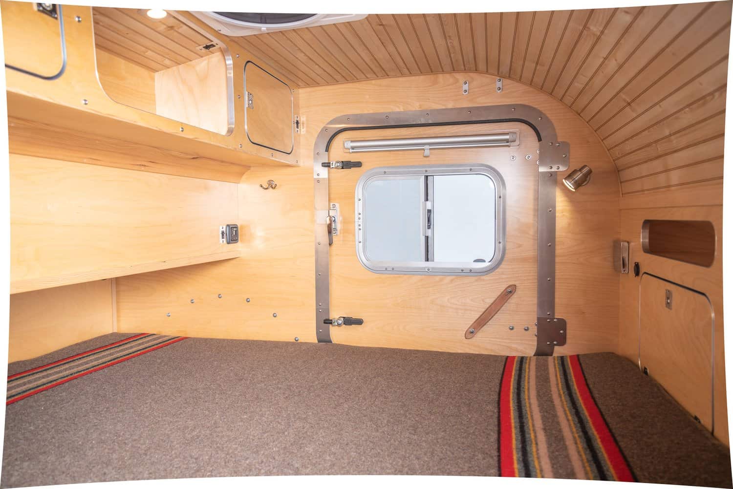 Inside the High Camp teardrop cabin looking toward a side door with a window
