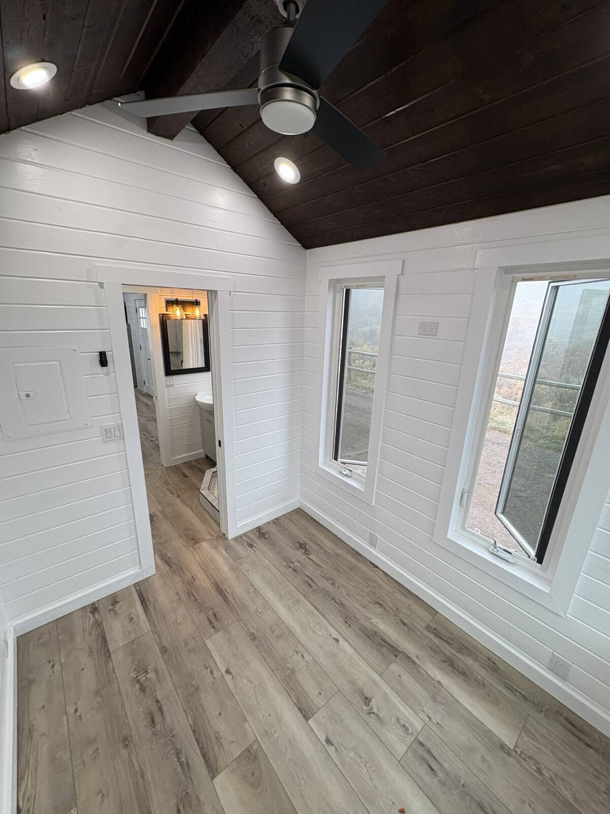 Main floor bedroom with vaulted ceiling and large windows in the custom tiny house
