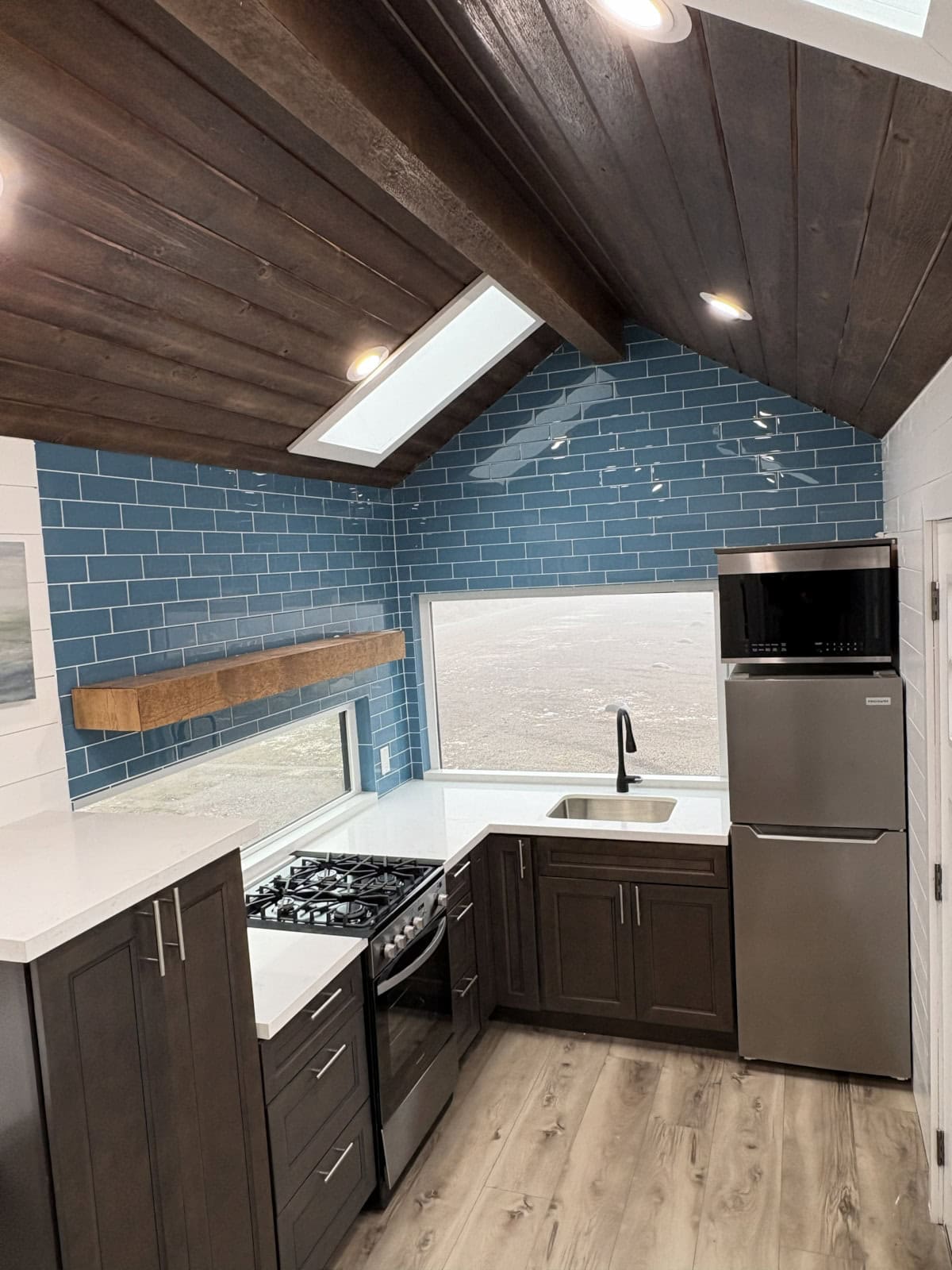 Custom tiny house kitchen with blue tile, stainless appliances, and quartz counters