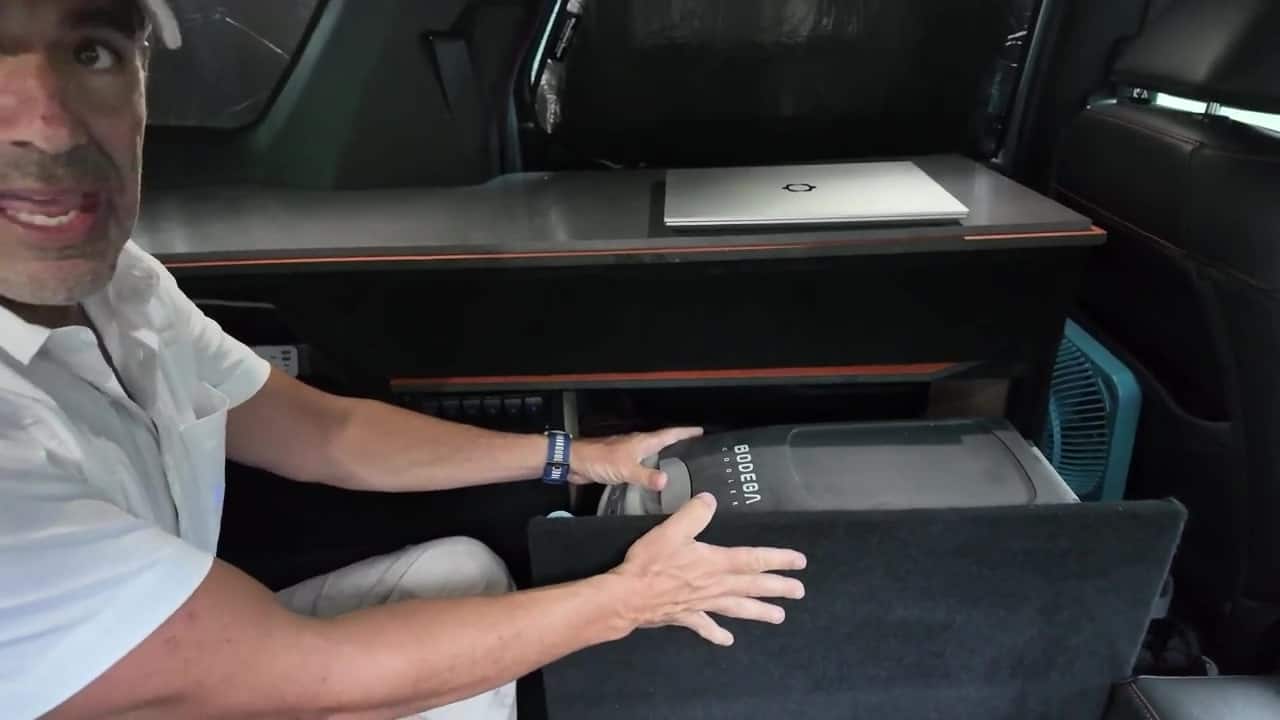12V Bodega cooler fridge tucked in a lower cabinet cubby beneath the sliding desk in Aaron's Honda Pilot camper