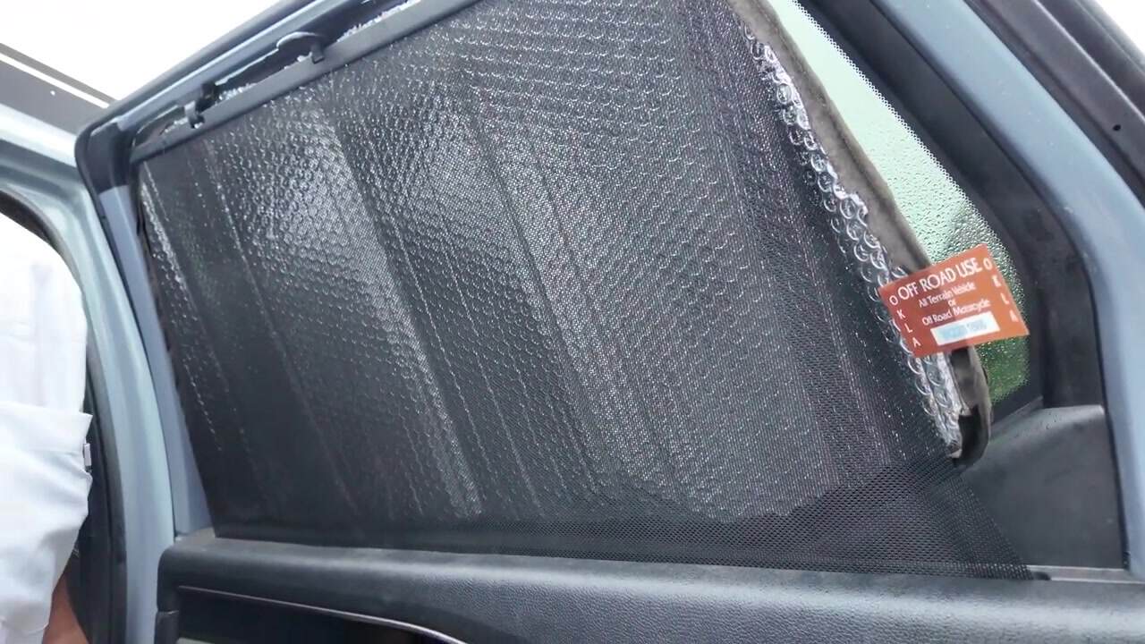 WeatherTech-style window blackout cover on the rear passenger door of Aaron's Honda Pilot camper, black interior face with silver bubble backing peeled back