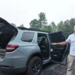 2024 Honda Pilot TrailSport conversion with black roof rack, rear hatch and passenger door open, Aaron presenting the build on a gravel lot