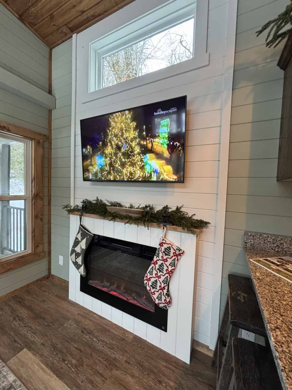 White shiplap fireplace surround with an electric fireplace, a wall-mounted TV, and a transom window above