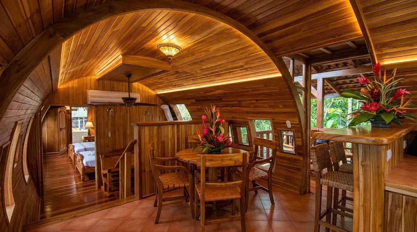Teak dining table, bar stools, and curved fuselage ceiling inside the Costa Verde 727 suite