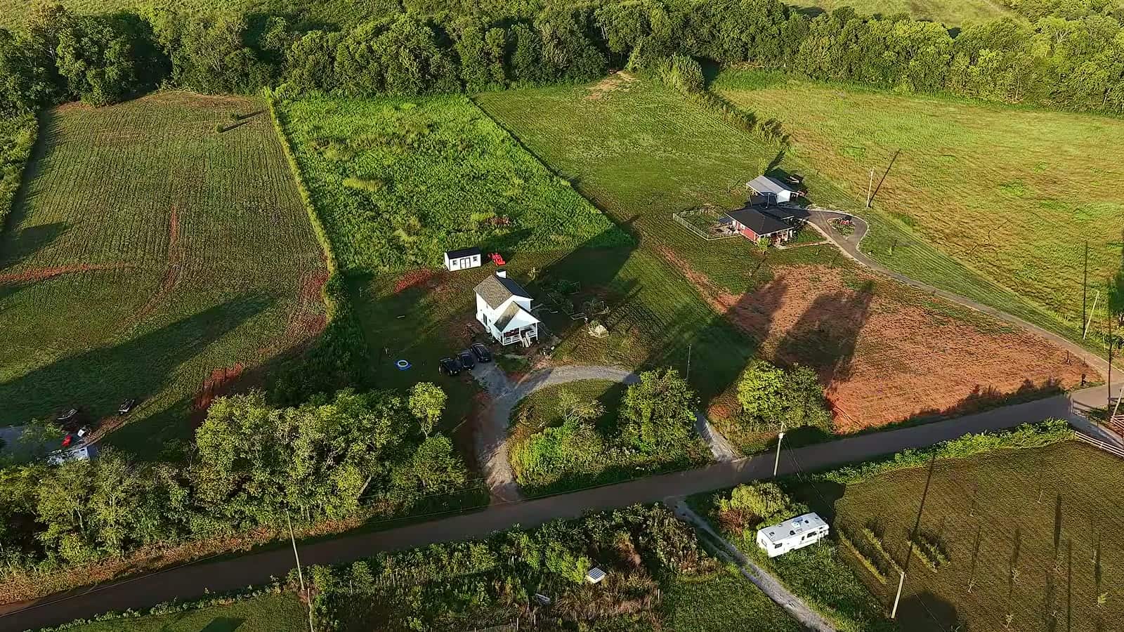 Aerial view of the Hursts' homestead with large garden plots, fields and the small white farmhouse among trees