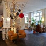 Hall 1 factory common: vintage caravan, wooden hut, retro lounge and plants in a former factory hall
