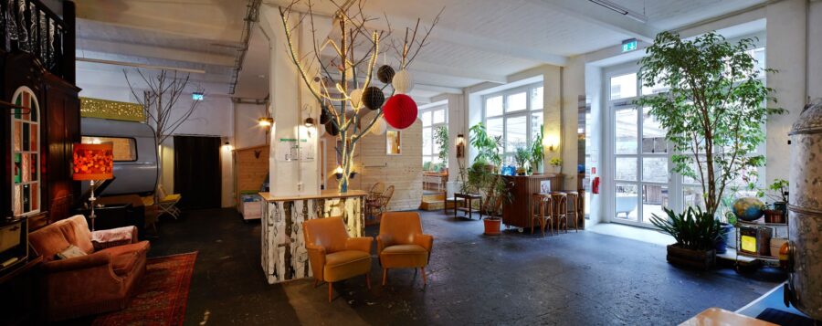 Hall 1 factory common: vintage caravan, wooden hut, retro lounge and plants in a former factory hall