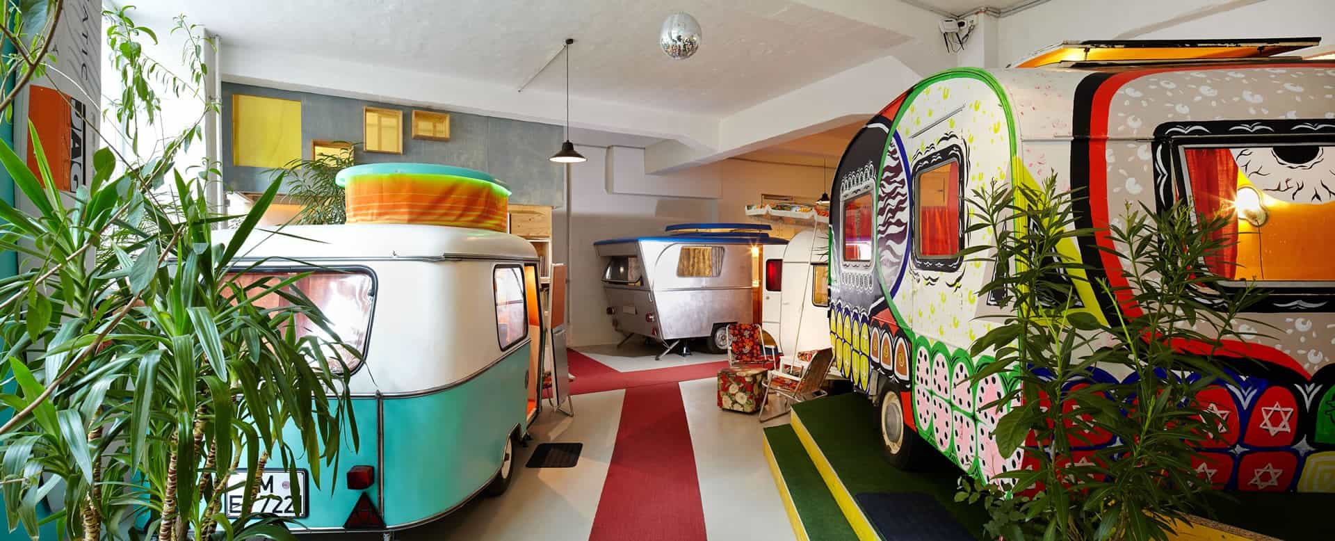 Hall 2 panorama: several vintage caravans parked in a bright factory hall with plants and a disco ball
