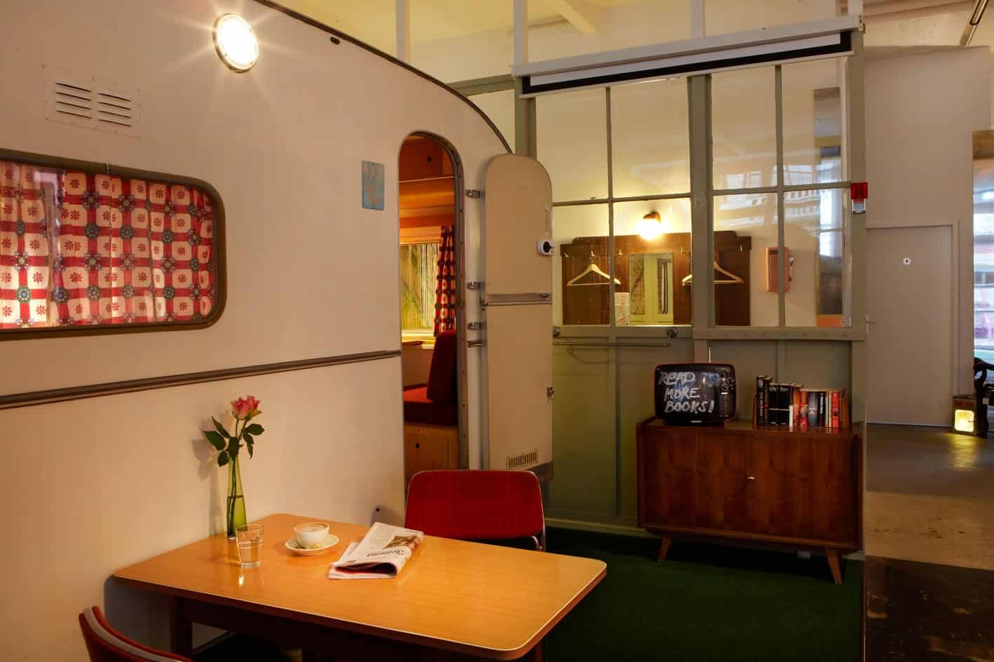 Cream vintage caravan Schwalbennest indoors, small table on green carpet, door open