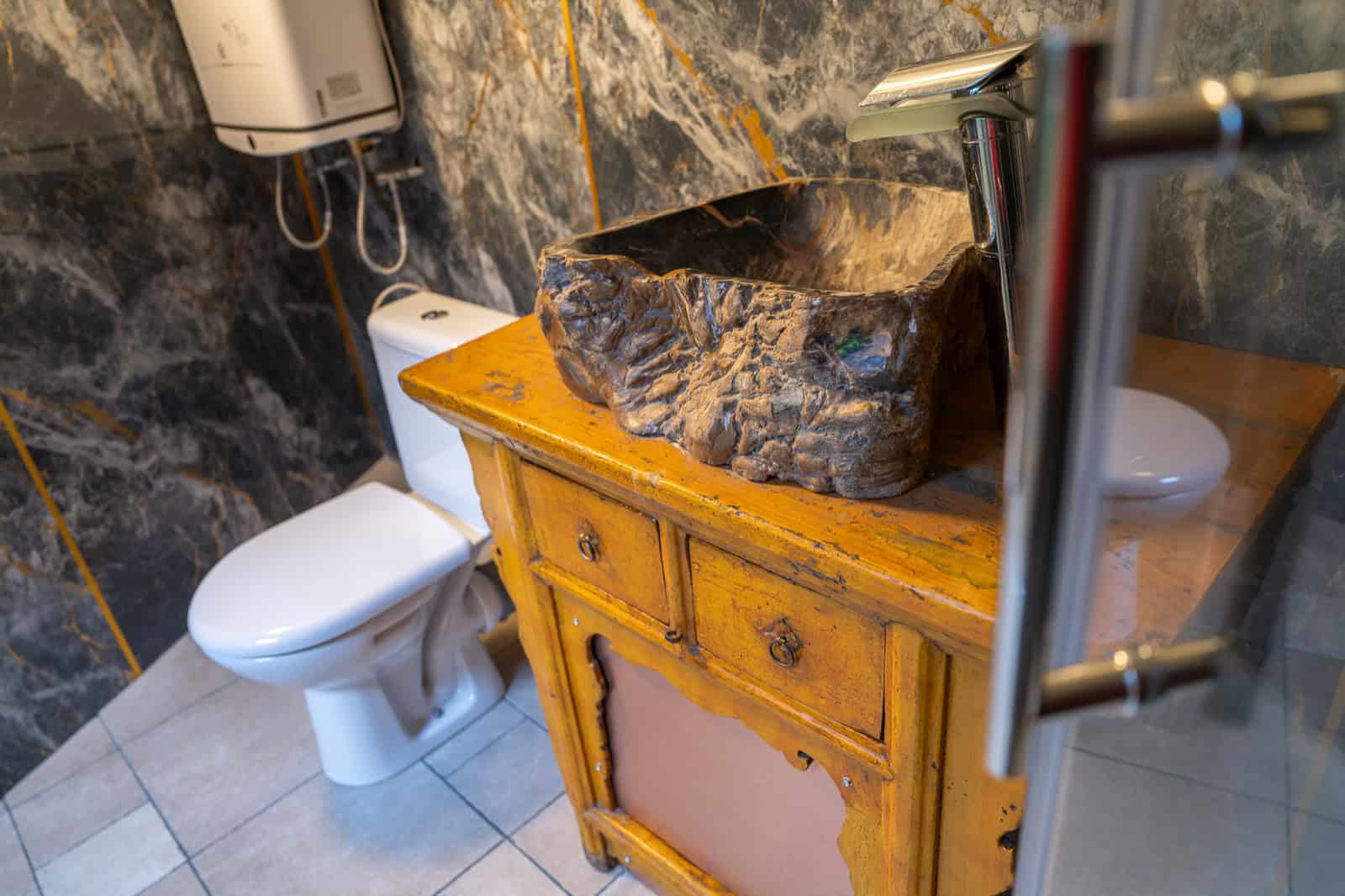 UFO Spaceship bathroom with a wooden vanity, stone vessel sink, and toilet