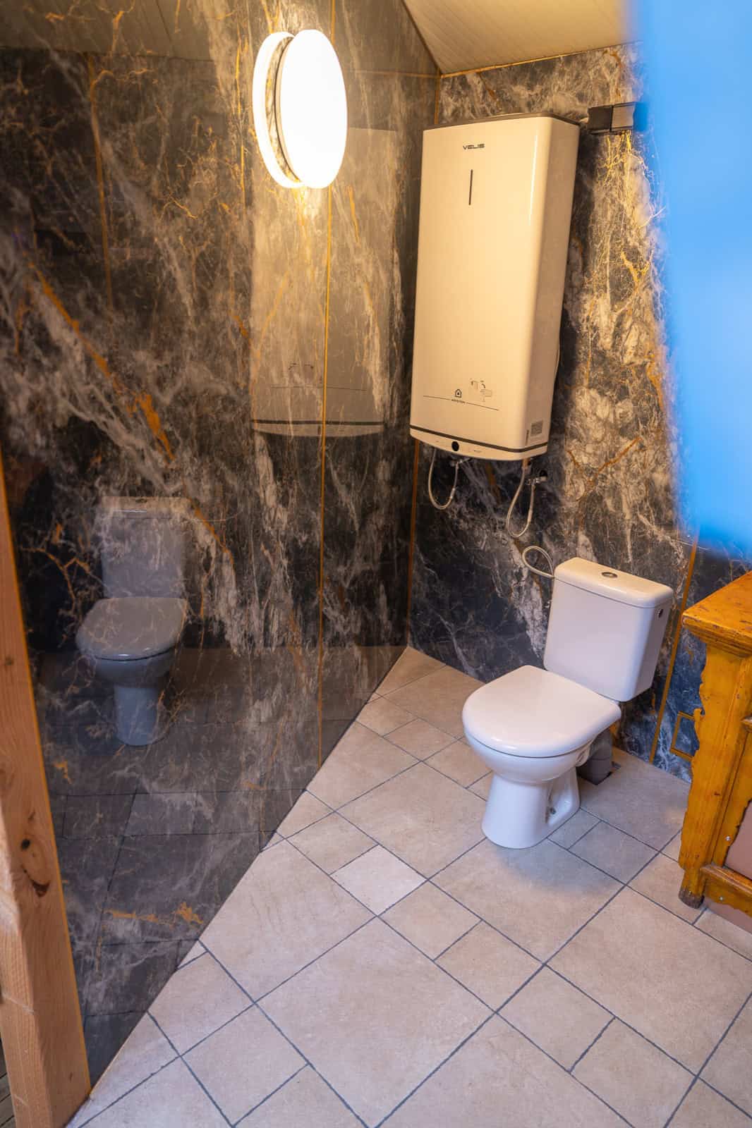 UFO Spaceship bathroom with marble-look walls, toilet, and water heater