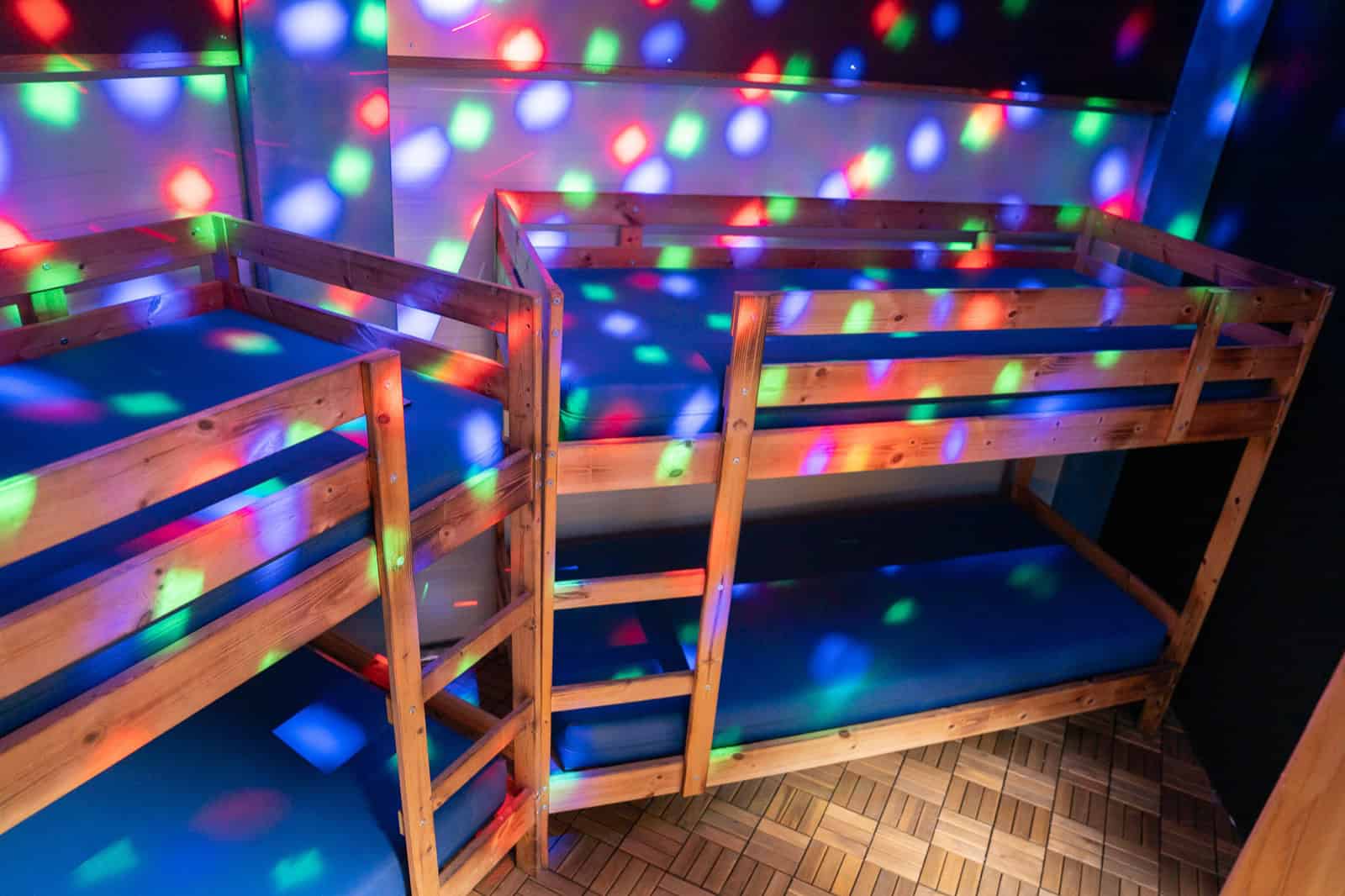 Wooden bunk beds in the UFO Spaceship lit with colorful disco lights