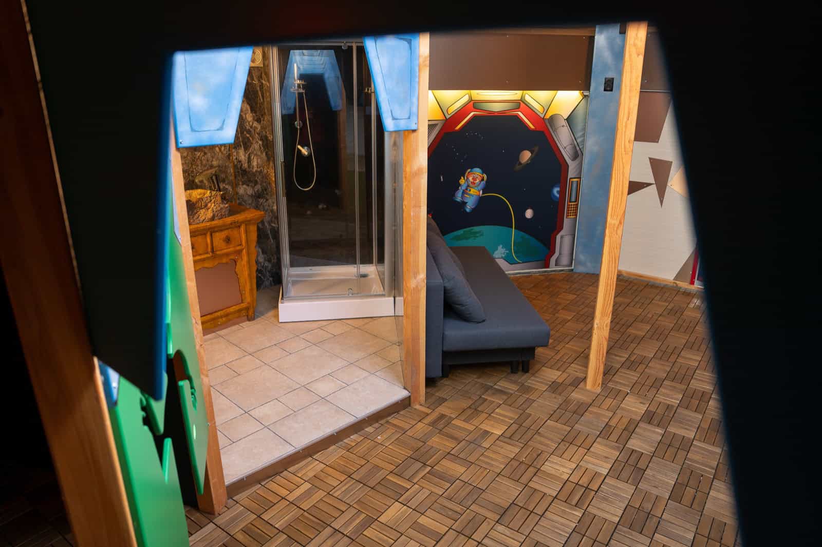 Inside the UFO Spaceship: wood floors, space-themed murals, sofa, and shower room