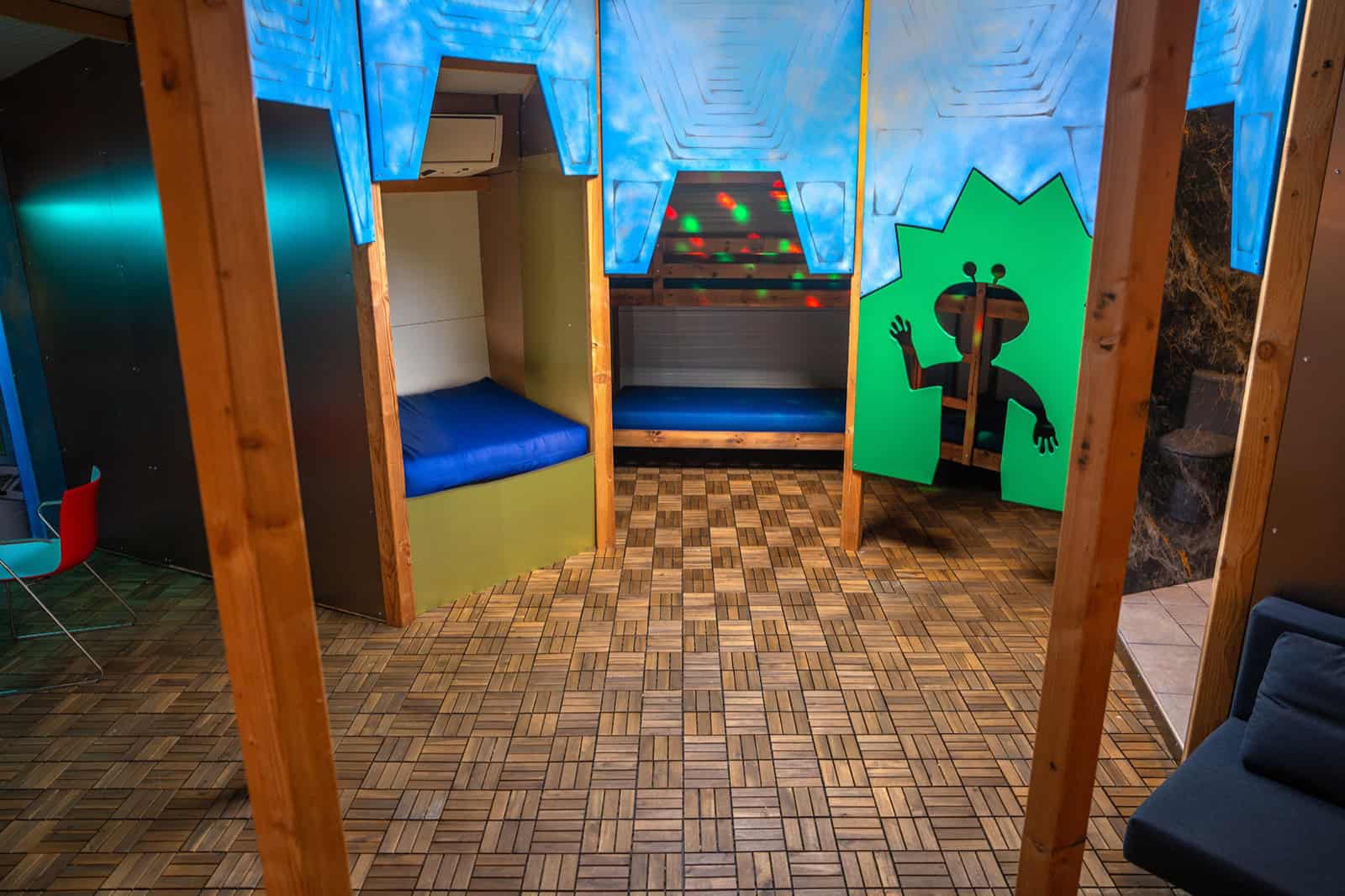 Kids cockpit play area in the UFO Spaceship with padded blue seats and a green alien cutout