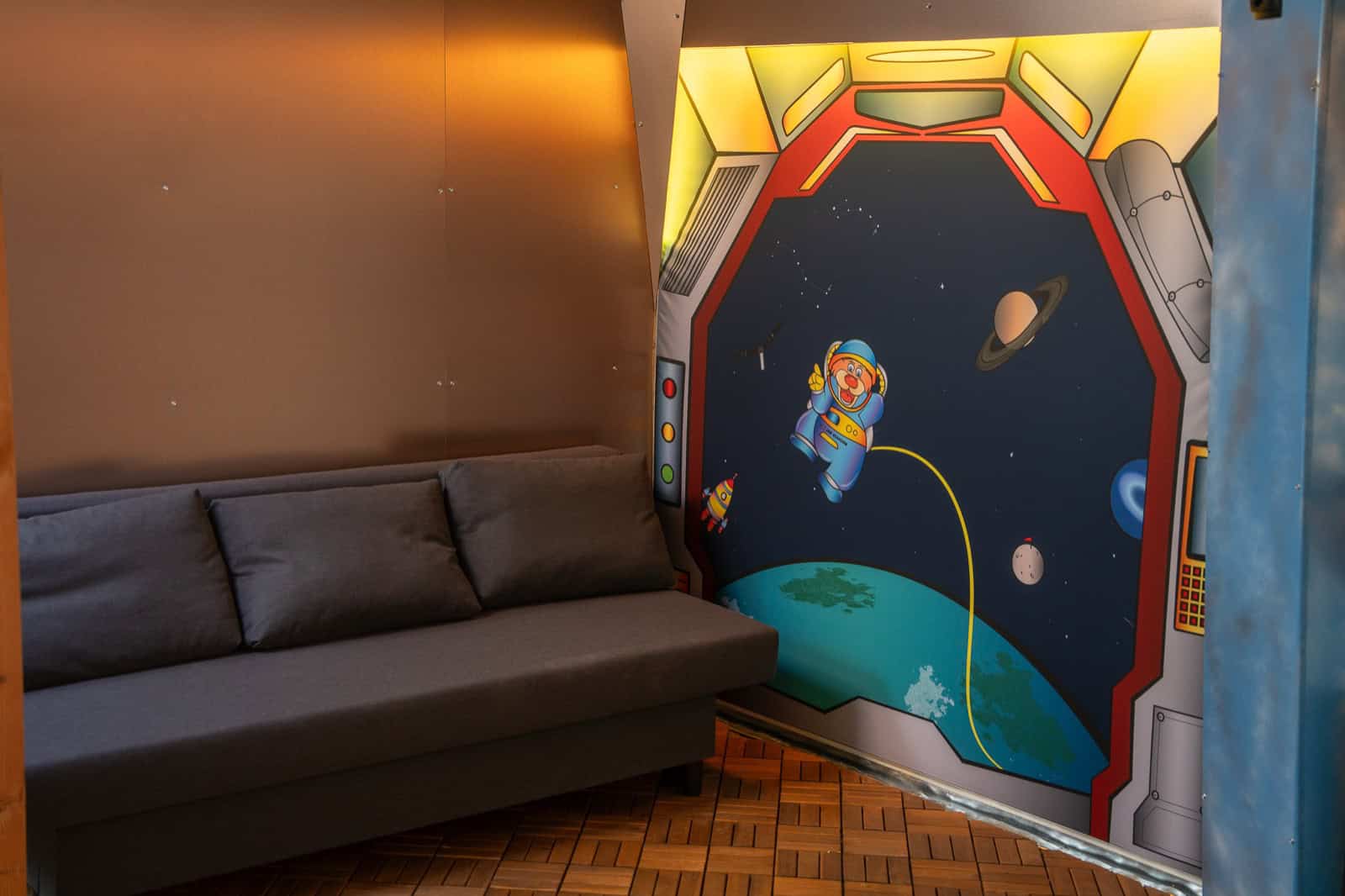 Grey sofa bed under a mural of an astronaut floating in space
