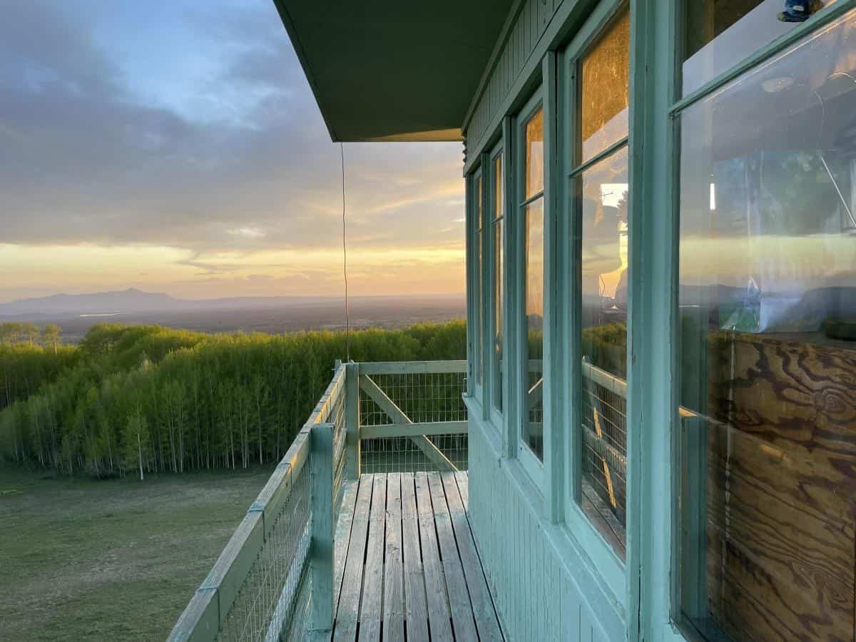 Cab corner and wraparound deck of Jersey Jim Lookout at sunset over forest