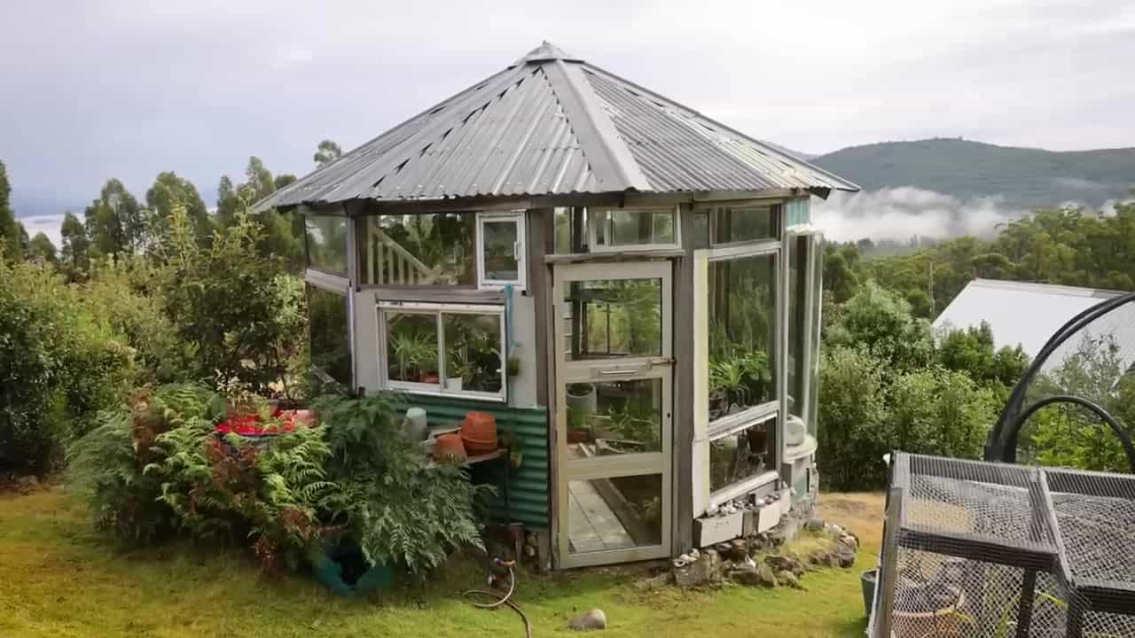 Octagonal greenhouse of recycled windows and corrugated roof on a misty Tasmanian hillside