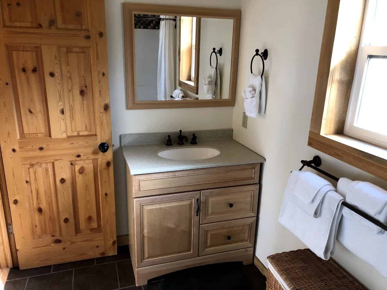 Wood vanity and mirror, with towels and a window reflected, no person