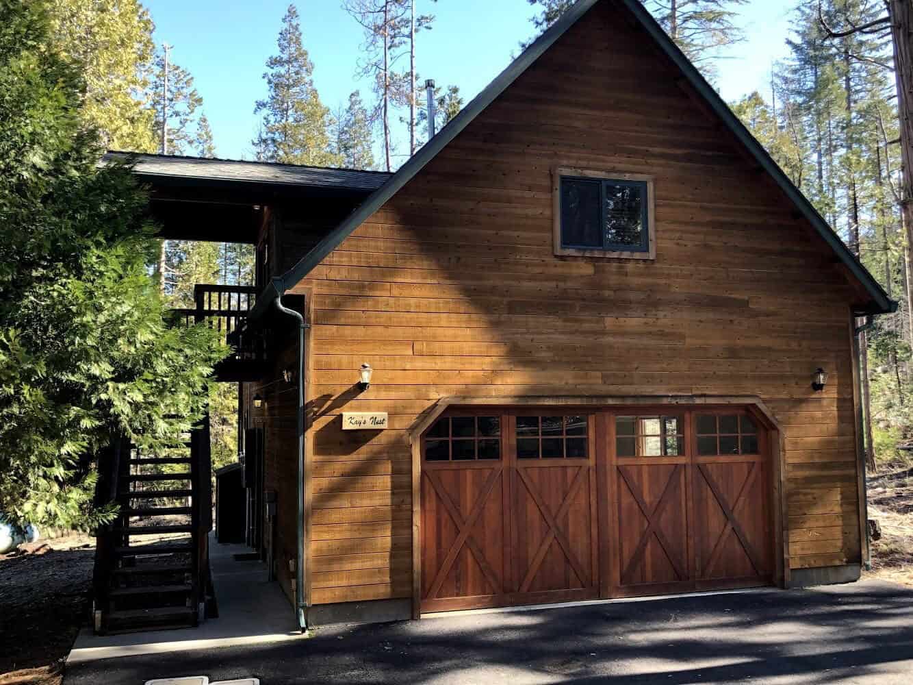 Two-story wood house in the pines with a wall sign that reads Kay's Nest