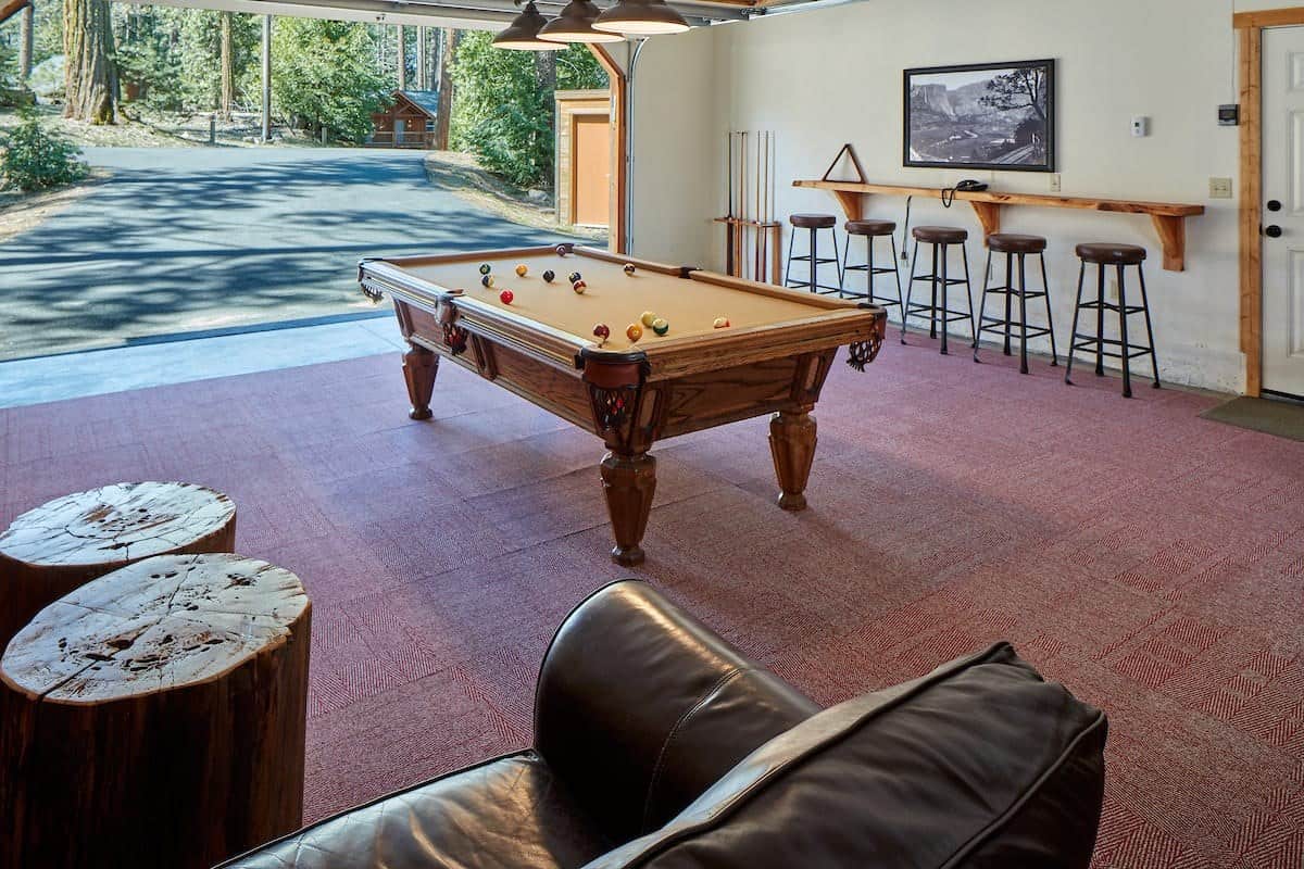 Game room with a pool table, bar stools along a counter, and an open door to the pines