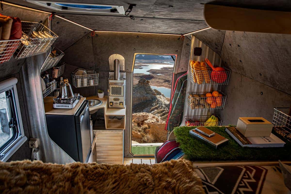 Kimbo 6 interior from the loft looking aft: wood galley counter and sink on the left, open rear door on a canyon, stainless Dickinson heater beside the door