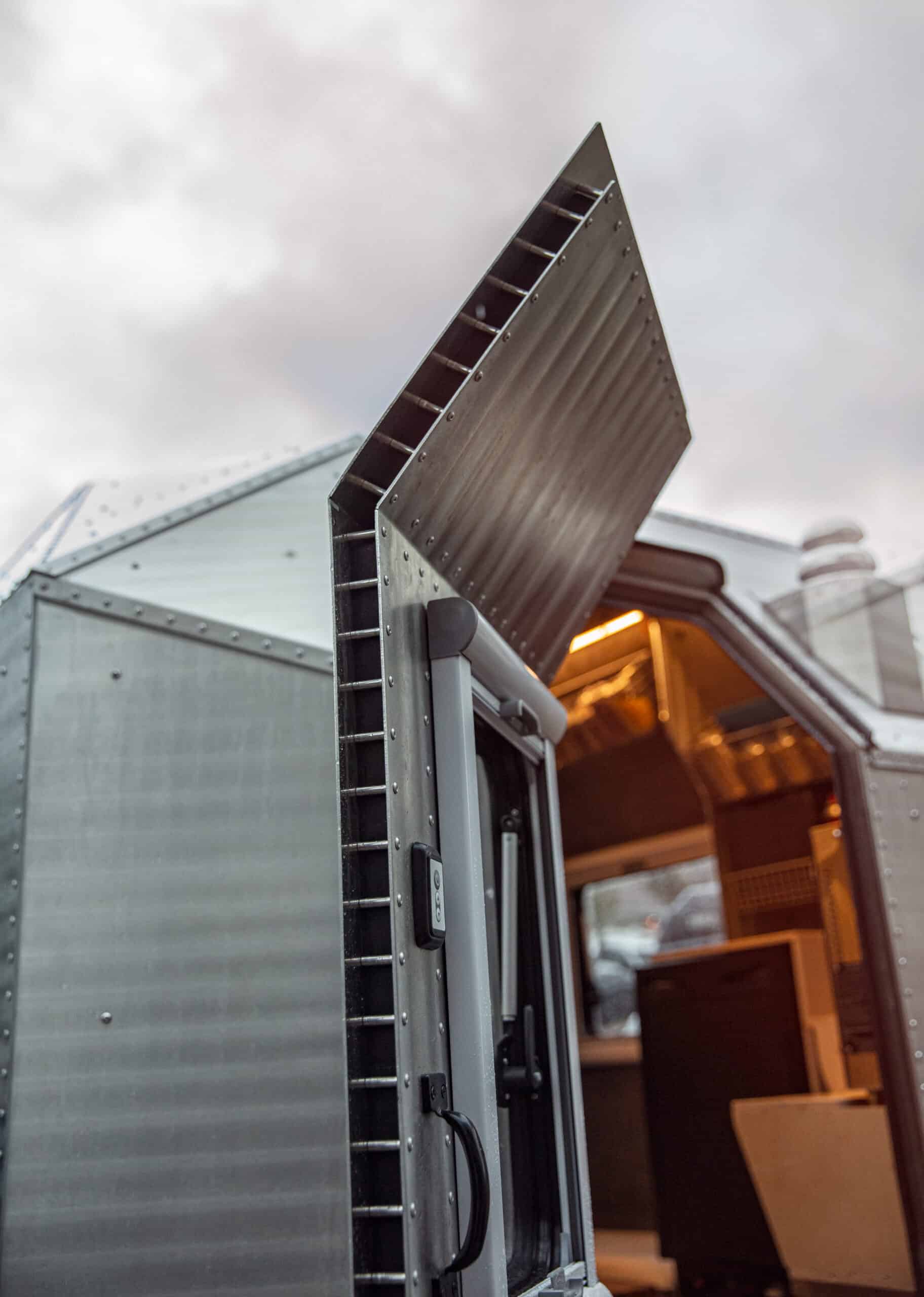 Mobile tiny house kitchen door with open hatch, compact and functional design.