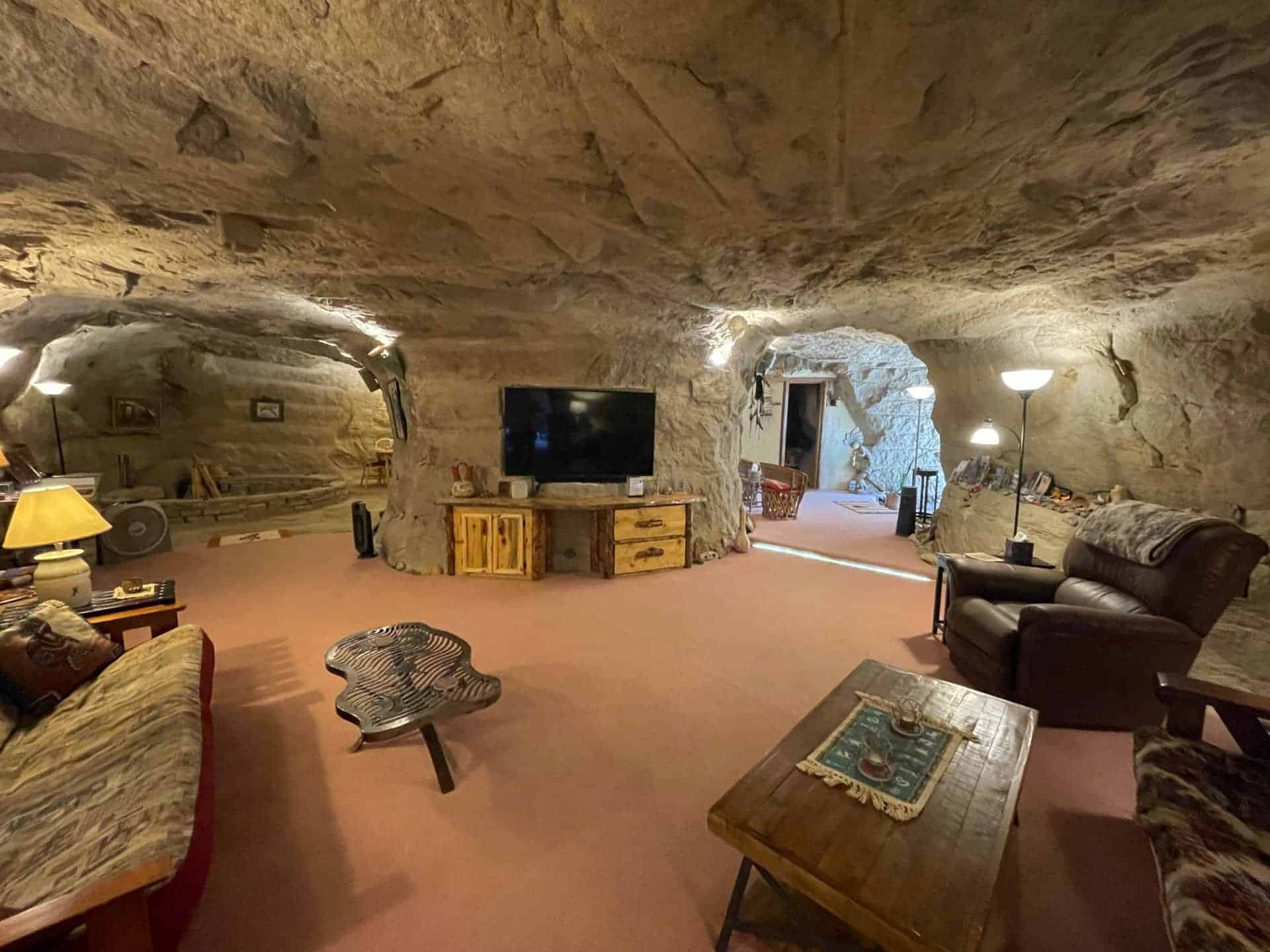 Living room in the cave: central sandstone pillar, sofas, television, terracotta carpet