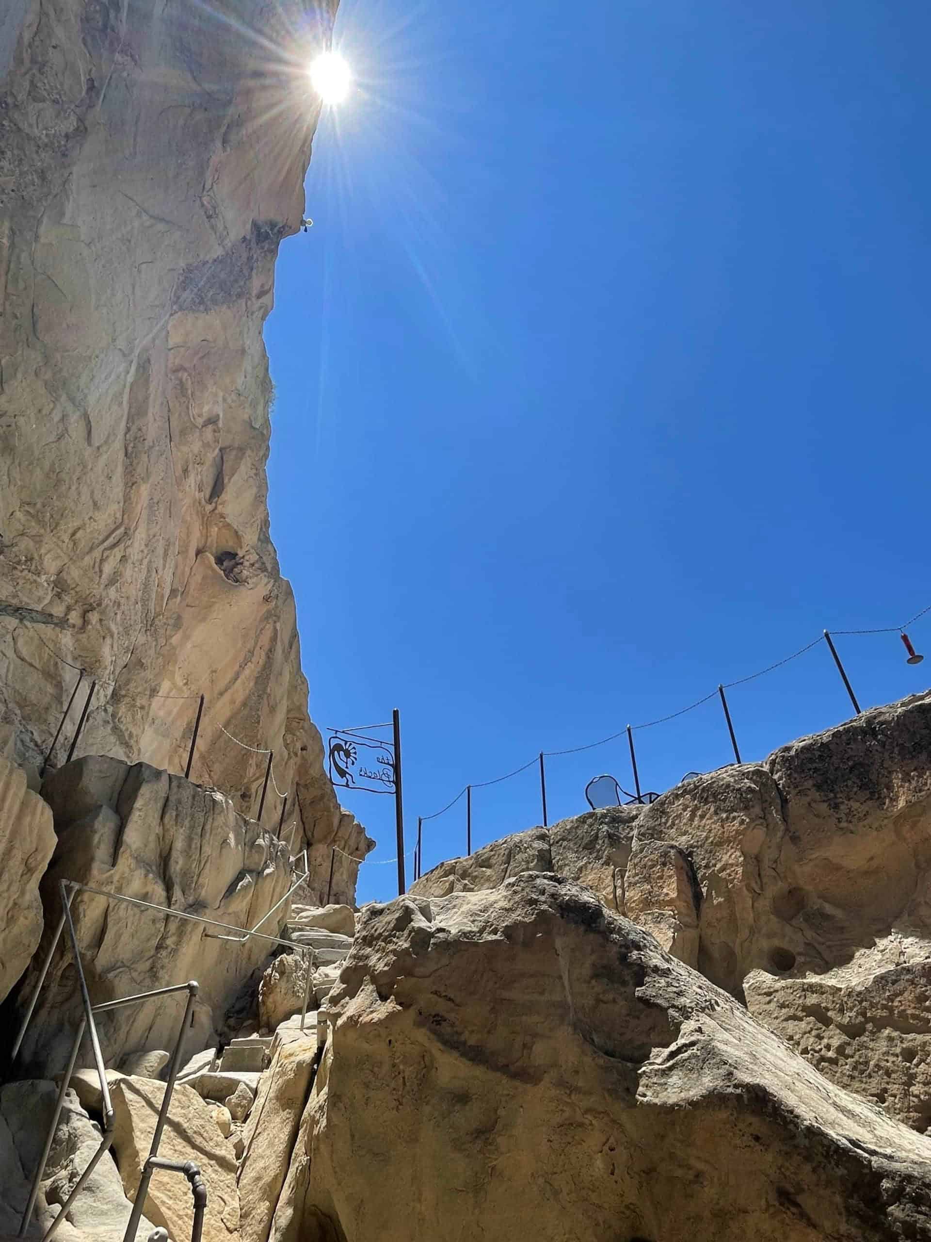 Sandstone steps and metal rail climbing to the Upper Patio, Kokopelli’s Cave sign on a pole