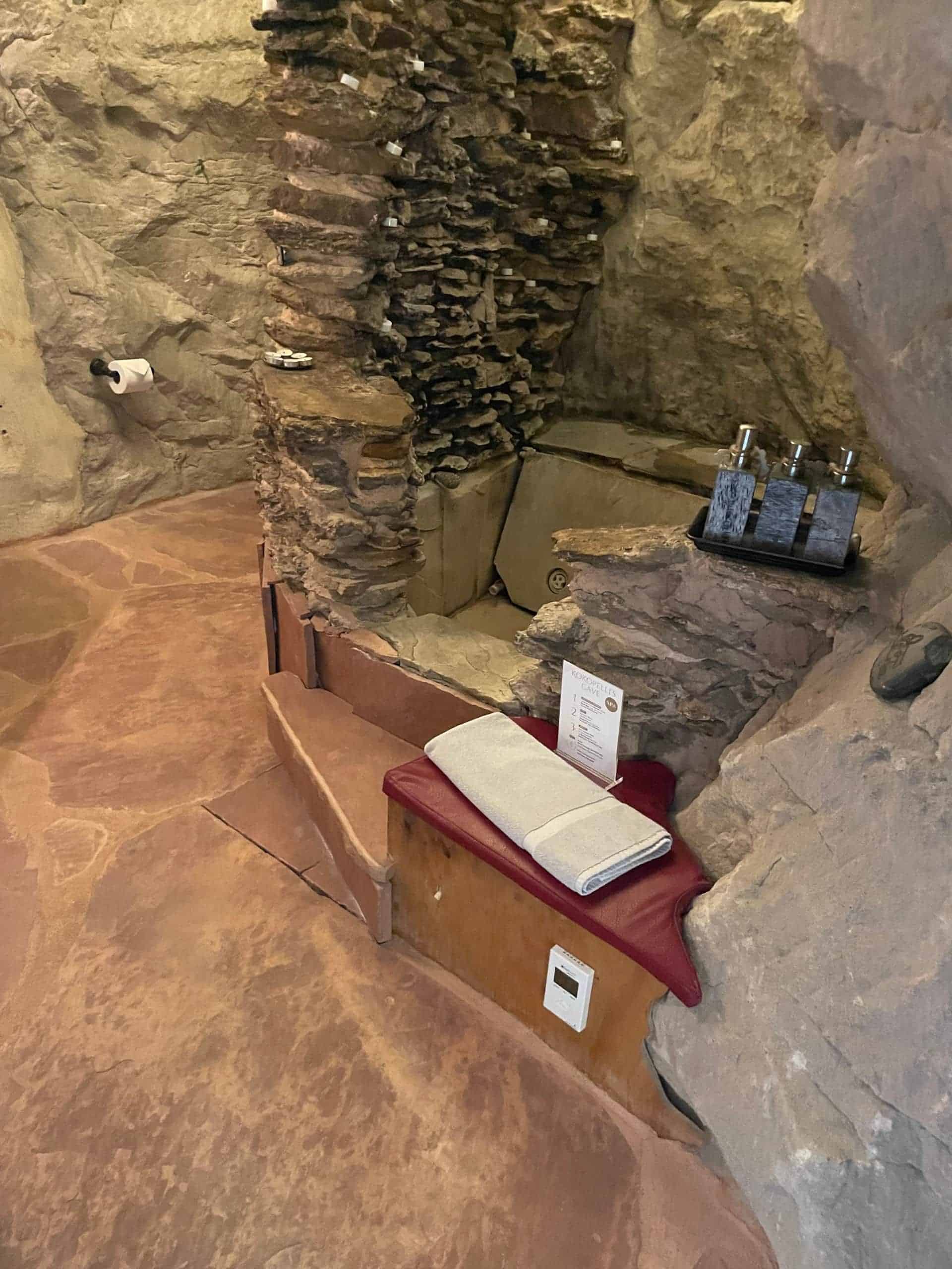 Stacked-stone Jacuzzi tub sunken in flagstone, candles in the stone, cave walls around it