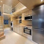 Modern tiny house kitchen with loft and large storage areas, showcasing efficient small space design.