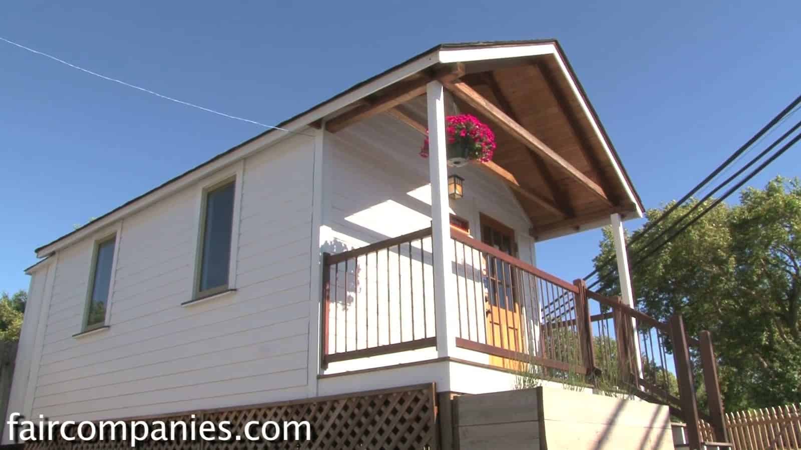 Side view of the 12-foot-wide Little House on a Trailer showing its porch, railings and lattice skirting that hides the trailer