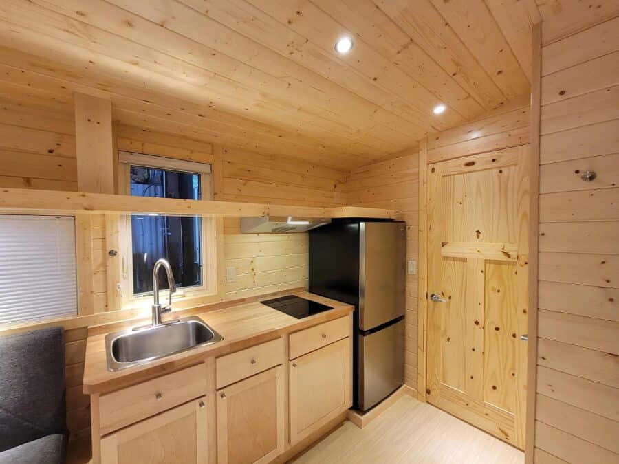 Electric eBoho tiny house kitchen with compact appliances and wooden interior.