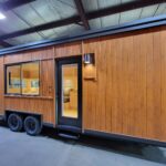 All-electric tiny house on wheels with wooden siding and modern design, ideal for small space living.